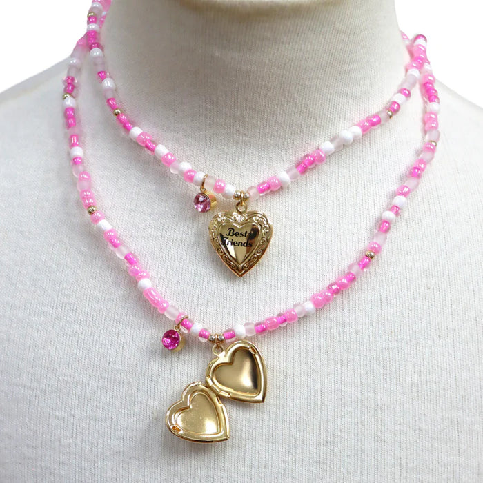 Two gold heart-shaped best friends pendants on pink beaded necklaces against a white background